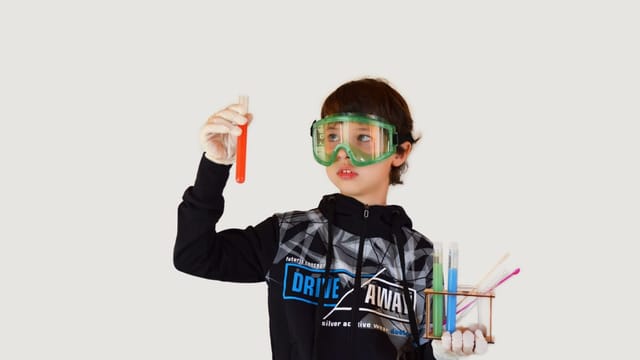 Jeune élève en blouse et lunettes de protection tenant un tube à essai