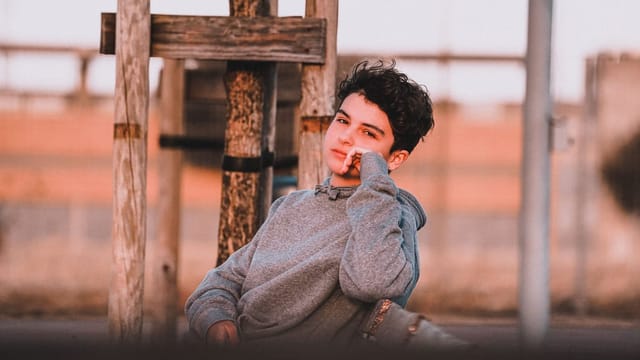 Adolescent pensif, la main près du visage