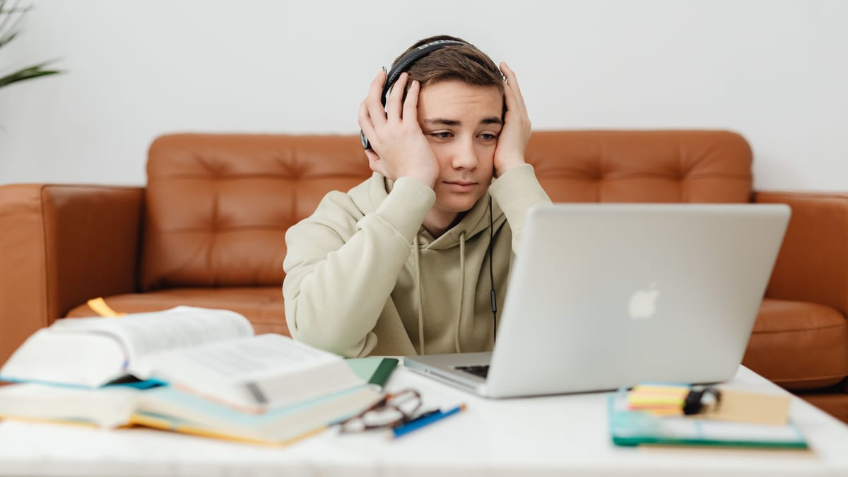 Adolescent dépassé devant son ordinateur portable lors d'un cours en ligne