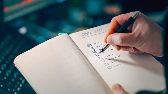 Main qui rédige une liste dans un carnet