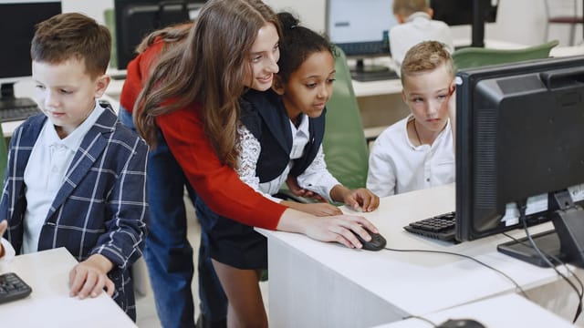 Enseignant et élèves devant un ordinateur en classe