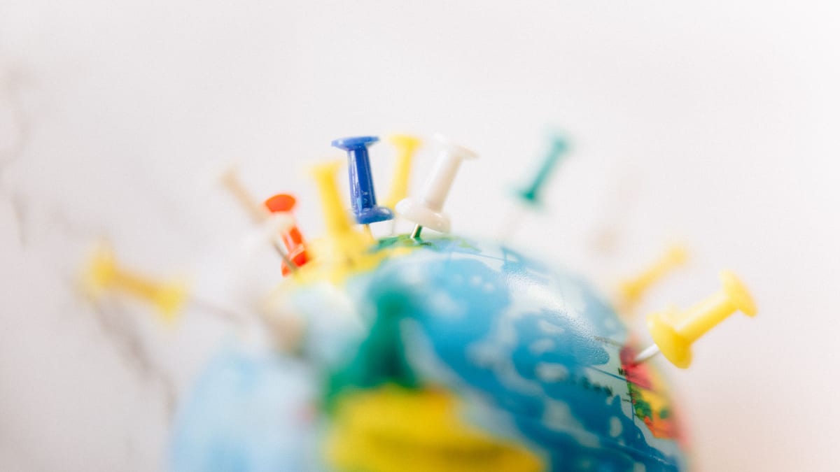 Globe terrestre marqué d'épingles multicolores sur différents pays