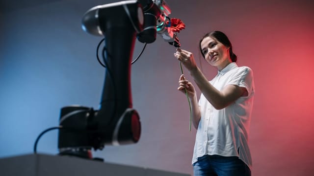 Bras robotisé tendant une fleur vers une personne