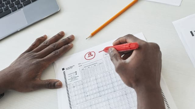 Main corrigeant une copie au stylo rouge