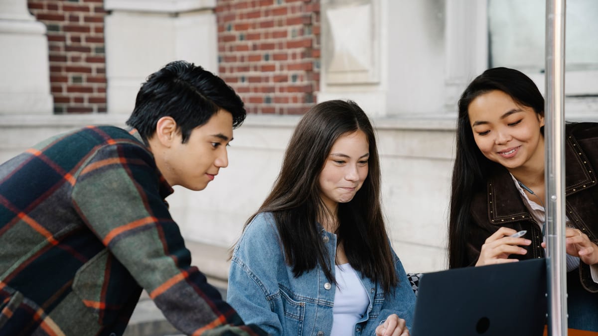 Trois étudiants regardant un ordinateur portable ensemble